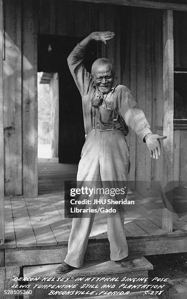Full length standing portrait of a mature African American man making elaborate hand gestures on the Lewis Plantation, on the steps to a building,...
