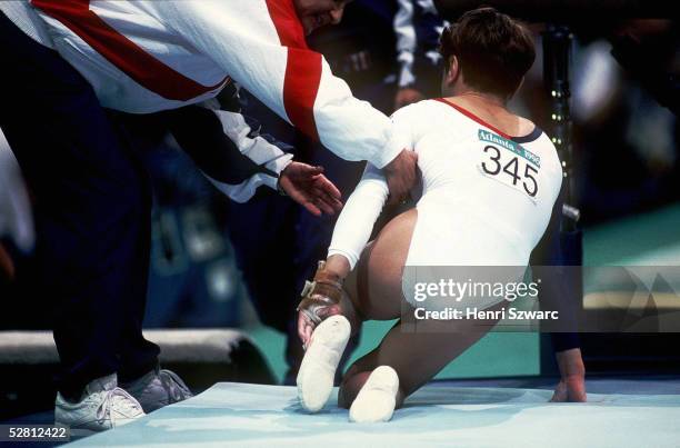 Mehrkampf Team Frauen 23.7.96, Trainer KAROLY beugt sich zu Kerri STRUG - USA die sich beim Sprung uebers Pferd verletzte.