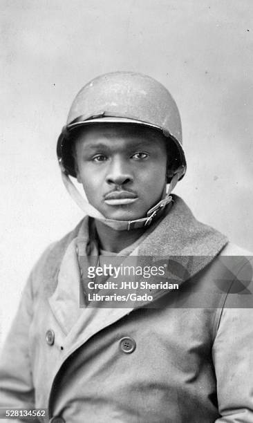 Half length portrait of an African American soldier, wearing a double-breasted jacket and helmet, neutral facial expression, circa 1940. From a...