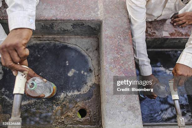 People fill bottles with water from public faucets at Latur railway station in Latur, Maharashtra, India, on Saturday, April 16, 2016. Hundreds of...