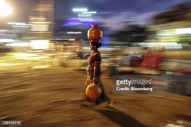 Water commuter carries a vessel of water on her head from the Vivekananda Chowk water tank in Latur, Maharashtra, India, on Saturday, April 16, 2016....