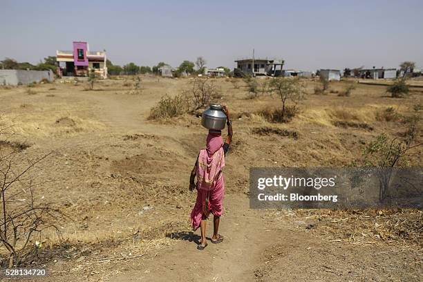 Woman carries a water container on her head filled from public drums at a village in Beed district, Maharashtra, India, on Friday, April 15, 2016....