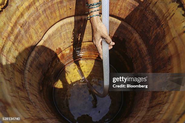 Woman siphons water from public drums at a village in Beed district, Maharashtra, India, on Friday, April 15, 2016. Hundreds of millions of people in...