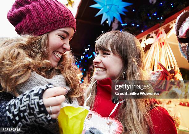 two young adult women having fun on a christmas market - julmarknad bildbanksfoton och bilder