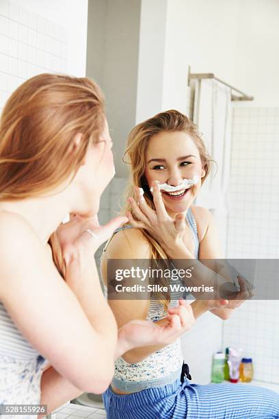 young adult woman in front of a mirror making a mustache with shaving foam - facial hair in women stock pictures, royalty-free photos & images