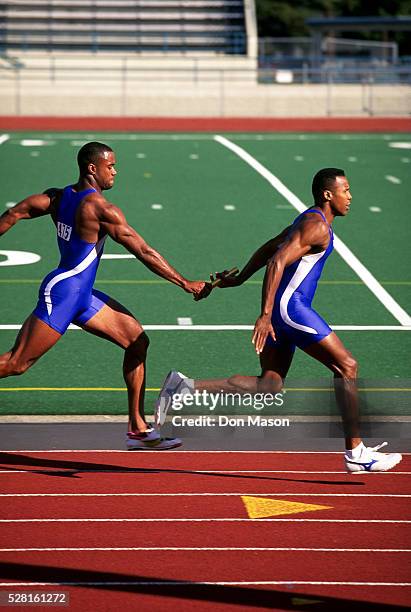 men passing the baton in 400 meter relay - track relay stock pictures, royalty-free photos & images