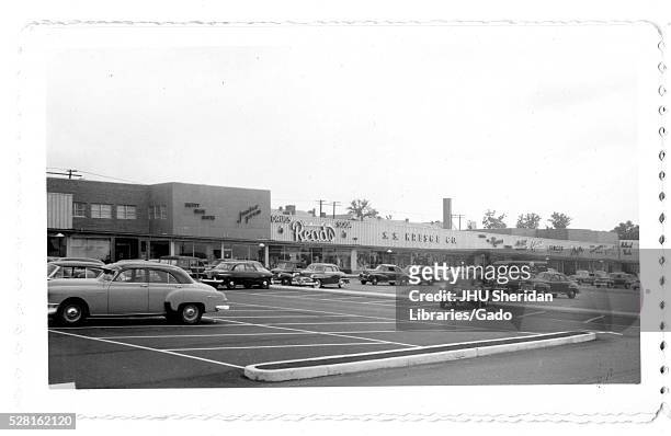 Photograph of the parking lot for the Northwood Shopping Center in Baltimore, Maryland, showing cars and commercial buildings such as Reads, S S...