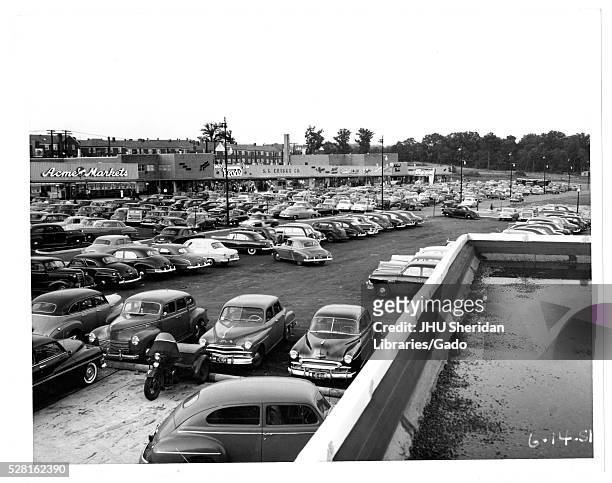 Photograph of the parking lot for the Northwood Shopping Center in Baltimore, Maryland, showing many cars and commercial buildings such as Acme...