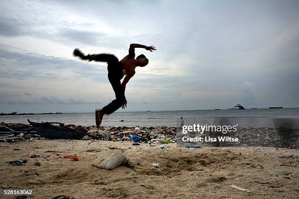 Young filipino boy flips through the air on the polluted beach of Baseco, Tondo district in Manila, Philippines on August 7, 2008. Photo by Lisa...