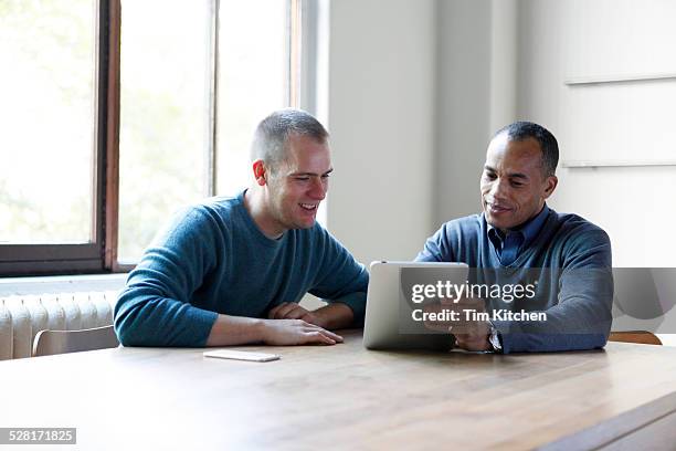 co-workers at table with digital tablet, smiling - receding stock pictures, royalty-free photos & images