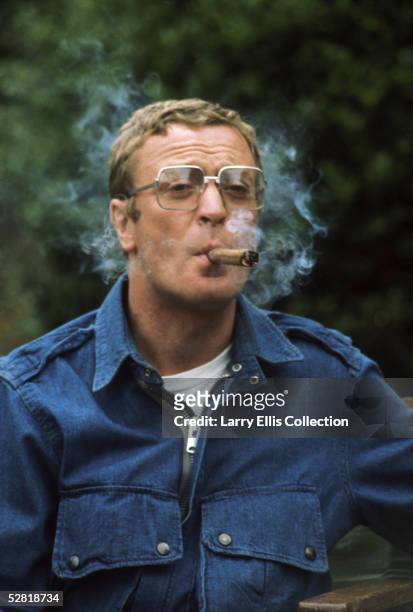 English film star Michael Caine enjoys a cigar, circa 1975.