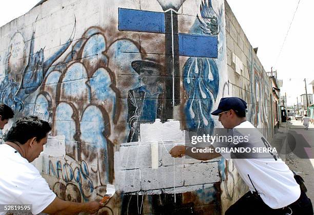 Agentes de la Policia Nacional Civil pintan el 13 de mayo de 2005 las paredes y muros de las viviendas de Ciudad del Sol, al sur de Ciudad de...