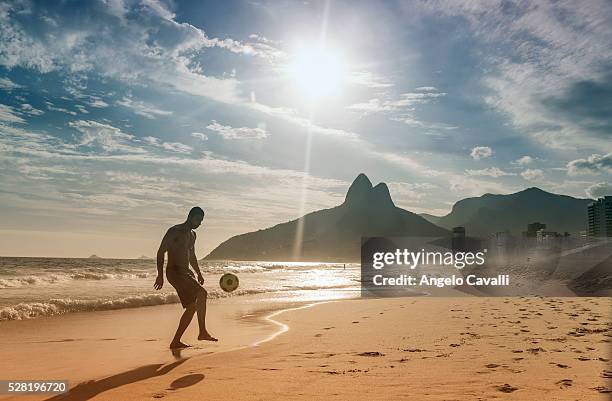 young man playing football on beach, ipanema, rio de janeiro, brazil - ipanema beach stock pictures, royalty-free photos & images