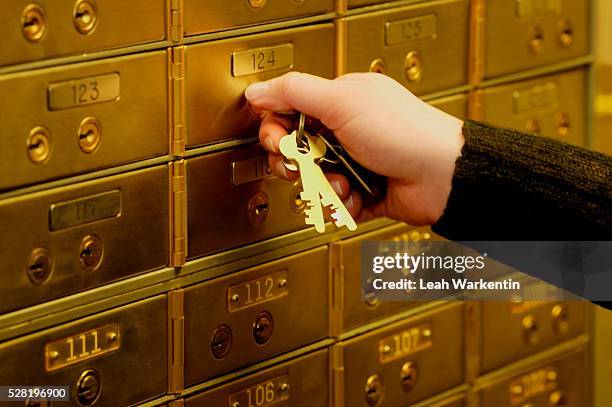 woman unlocking safe deposit box - safe deposit box stock pictures, royalty-free photos & images