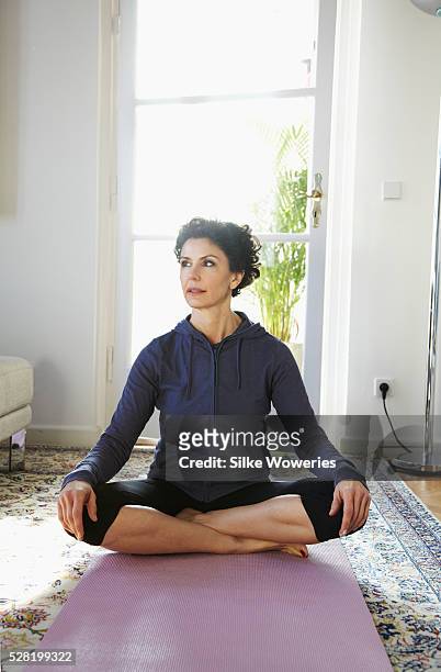 mid-adult woman doing yoga at home - 50 59 years stock pictures, royalty-free photos & images