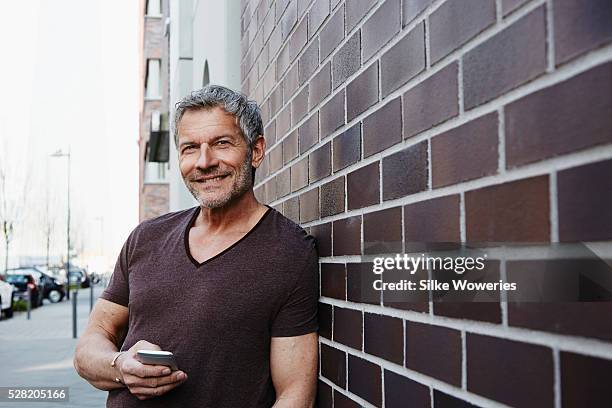 man standing in front of modern building in city - 50 59 years stock pictures, royalty-free photos & images