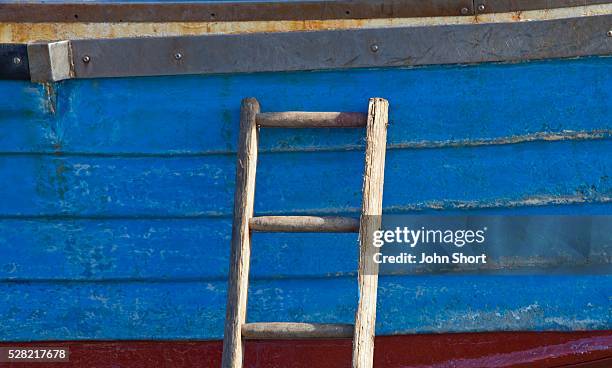 a wooden ladder propped against the side of a boat - craster stock pictures, royalty-free photos & images