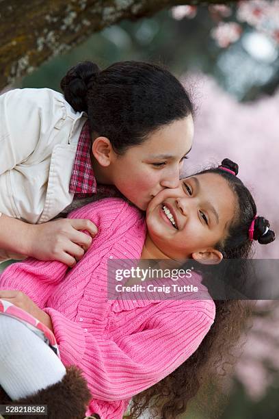 girls playing under a cherry blossom tree - cherry kiss 個照片及圖片檔