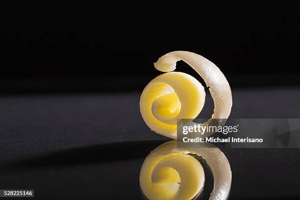 close up of a round curl of butter with reflection on a black background - butter curl stock pictures, royalty-free photos & images