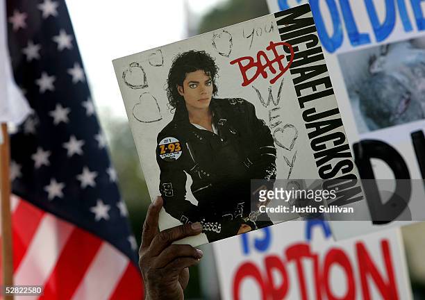 Supporter of singer Michael Jackson holds a copy of Jackson's album "Bad" as he arrives at the Santa Barbara County Courthouse for another day of...