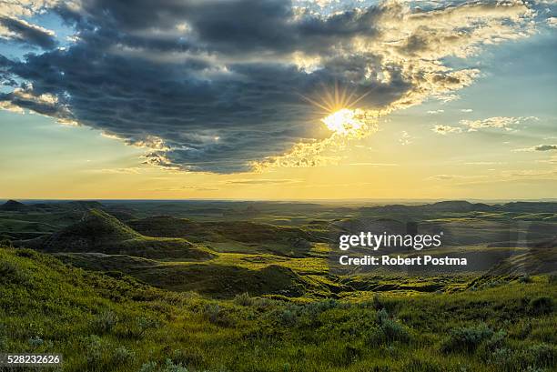 the sun shines through a cloud over the killdeer badlands, grasslands national park; saskatchewan, canada - グラスランズ国立公園 ストックフォトと画像