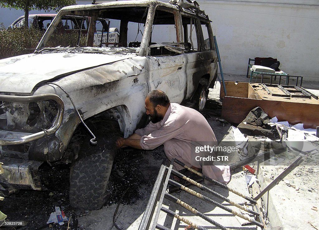 An Afghan man works on a damaged vehicle