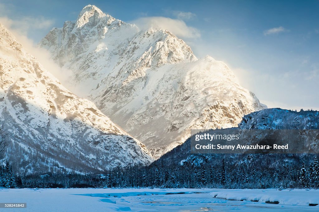 Sun shining on Mt. Yukla with frozen Eagle River in the foreground, Chugach Mountains, Chugach State Park, Southcentral Alaska, Winter.