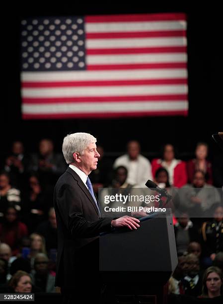 Michigan Governor Rick Snyder stands and listens the boos of the crowd when he takes to the stage to speak before U.S. President Barack Obama speaks...