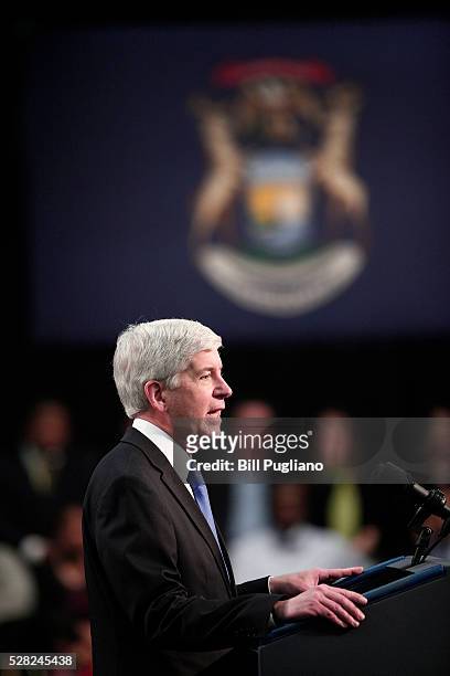 Michigan Governor Rick Snyder stands and listens the boos of the crowd when he takes to the stage to speak before U.S. President Barack Obama speaks...