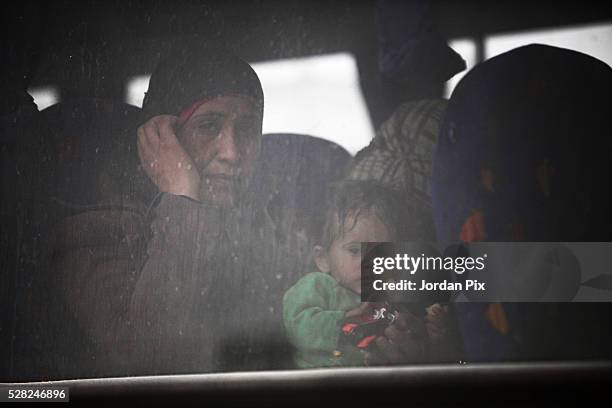 Syrian refugees sit on a bus that will take them to a camp at the Jordanian military crossing point of Hadalat at the border with Syria after a long...
