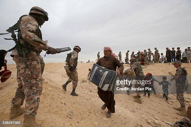 Syrian refugees who have arrived at the Jordanian military crossing point of Hadalat at the border with Syria are checked with a metal detector...