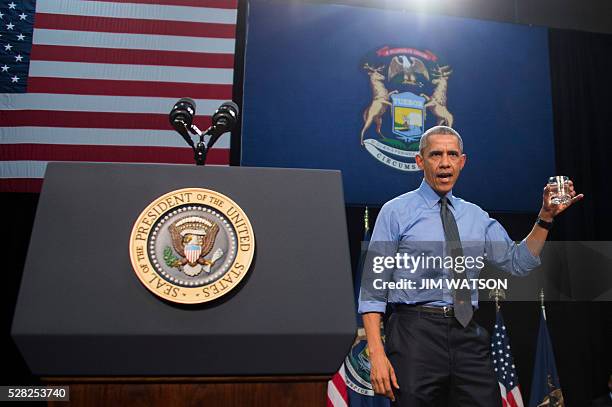 President Barack Obama holds up a glass of water as he speaks at Flint Northwestern High School in Flint, Michigan, May 4, 2016 after meeting with...