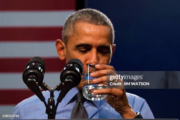 President Barack Obama drinks a glass of water as he speaks at Flint Northwestern High School in Flint, Michigan, May 4, 2016 after meeting with...