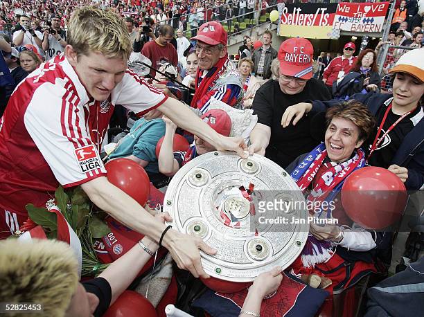 Bastian Schweinsteiger of FC Bayern Munich presents the trophy to handicapped fans after the Bundesliga match between FC Bayern Munich and 1. FC...