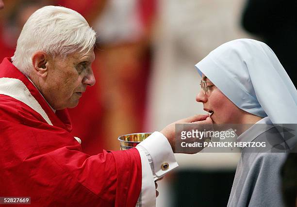 Pope Benedict XVI gives the Holy Communion to a nun during a mass of ordination of 21 new priests in St-Peter's basilica at the Vatican, 15 May 2005....