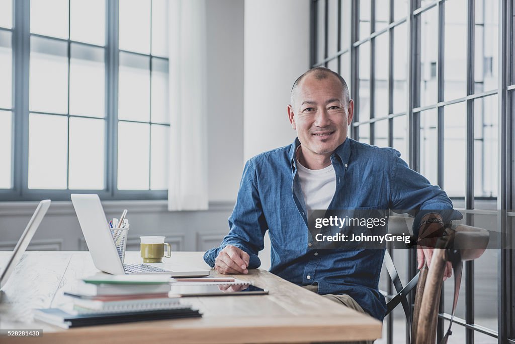 Creative mature man at desk in modern office