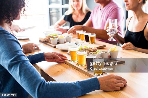 group of friends enjoying lunch & craft beer tasting - speciaalbier stockfoto's en -beelden