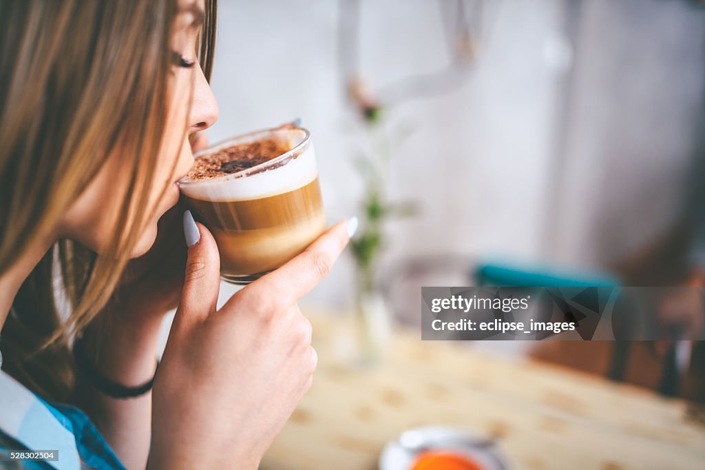 Jovem mulher atraente, desfrutando de uma xícara de café