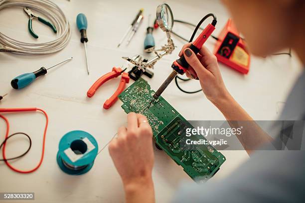 woman soldering a circuit board in her office. - soldered stock pictures, royalty-free photos & images