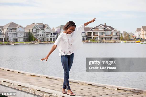 teenage girl balancing on the rail of a pier in a residential lake neighborhood; edmonton alberta canada - edmonton house stock pictures, royalty-free photos & images