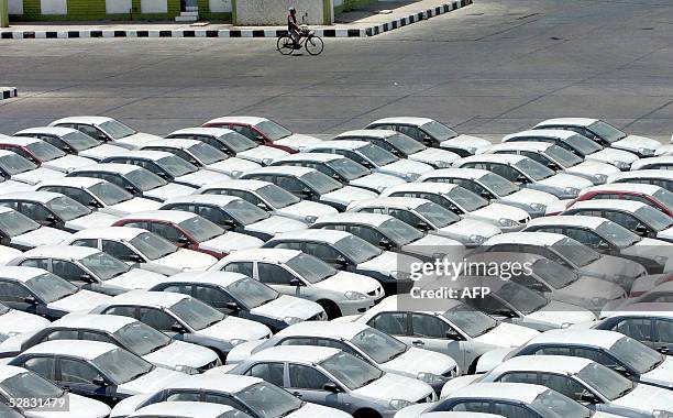 Pakistani cyclist rides past rows of new cars, parked on the dockside at Karachi, 16 May 2005. Pakistani car imports are on the rise after the local...