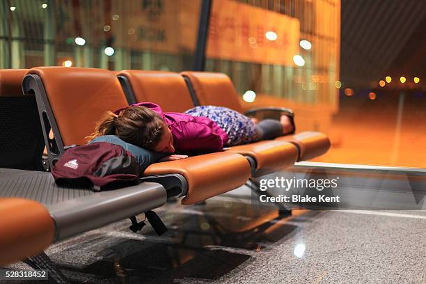 a girl sleeping on chairs at an airport; beijing, china - jet lag 個照片及圖片檔