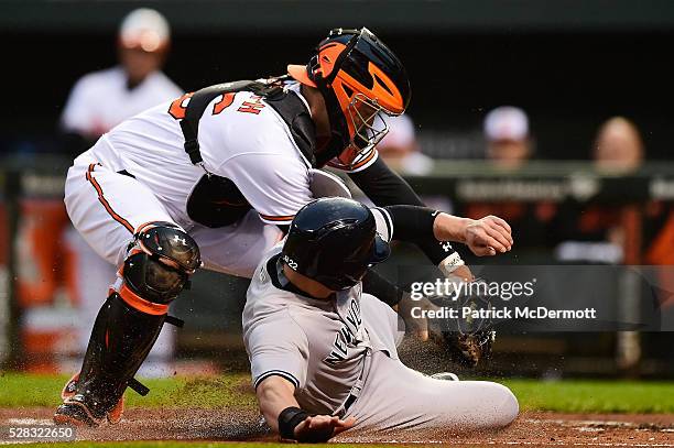 Jacoby Ellsbury of the New York Yankees is tagged out at home plate by Caleb Joseph of the Baltimore Orioles in the first inning during a baseball...