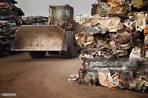 a tractor driving through stacks of compacted rubbish - schrottpresse stock-fotos und bilder