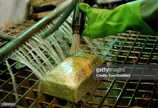 Mine worker cleans a newly poured gold bar at Driefontein Gold Mine near Carltonville, South Africa. The mine is owned by Gold Fields Ltd. Who...