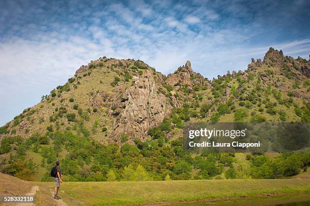 man with backpack looking up at sky and mountains; sutter buttes california united states of america - butte rocky outcrop stock pictures, royalty-free photos & images