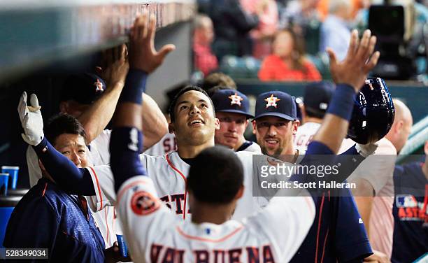 Carlos Correa of the Houston Astros is greeted in the dugout by Luis Valbuena after Correa hit a solo home run in the fourth inning off Casey Fien of...