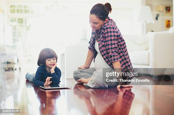 small boy with his mother using a digital tablet - auf dem boden sitzen stock-fotos und bilder