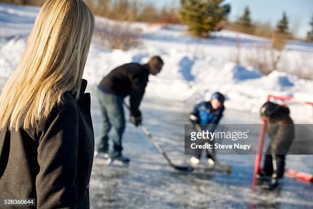 mother watching father and sons play hockey - hockey mom stock pictures, royalty-free photos & images