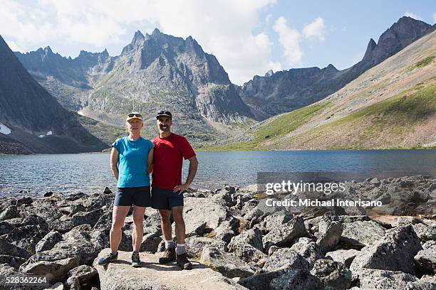 couple posing beside a lake in a valley with rugged mountains in the background; yukon, canada - active baby boomer stock pictures, royalty-free photos & images